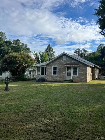 a view of a yard in front of a house with a large tree