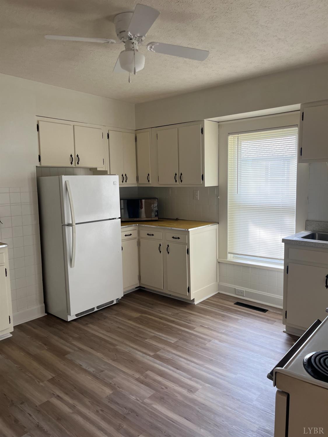 1109 Amherst Avenue Altavista, VA 24517 - Photo 5 of 23 a kitchen with a refrigerator a stove top oven a counter space and wooden floor