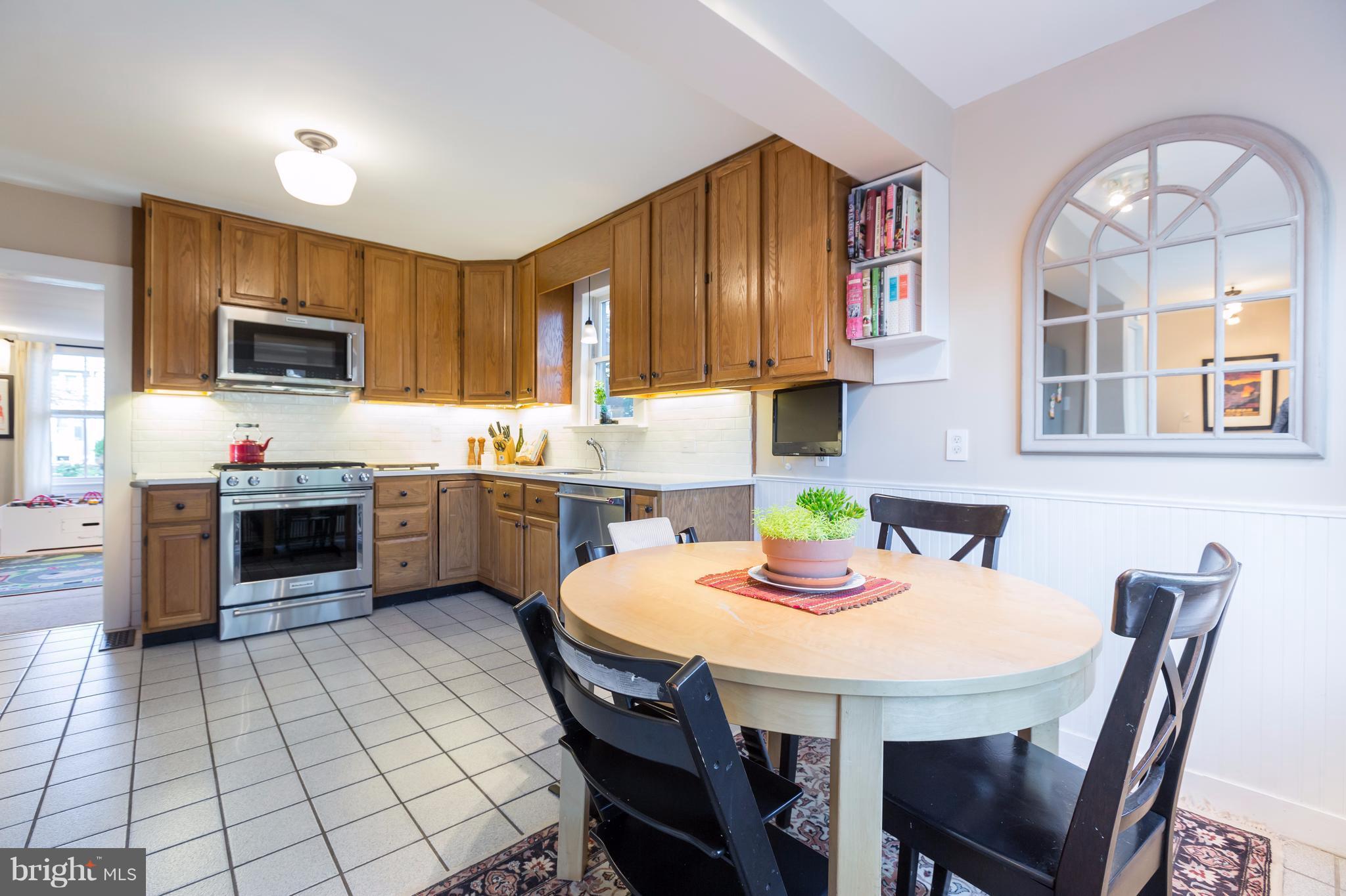 1405 Ridge Road Baltimore, MD 21228 - Photo 11 of 30 a kitchen with stainless steel appliances a stove a sink a microwave a dining table and chairs
