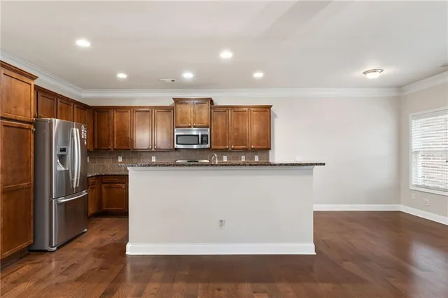 a kitchen with stainless steel appliances granite countertop a refrigerator a sink a stove a microwave and wooden floor