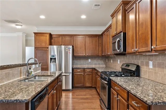 a kitchen with stainless steel appliances granite countertop a sink a stove and a refrigerator