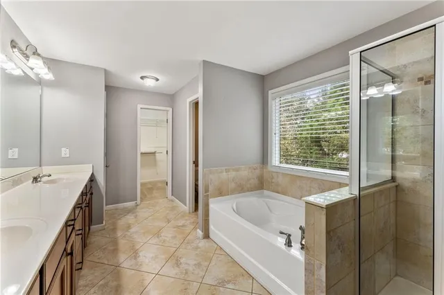 a spacious bathroom with a tub sink and mirror