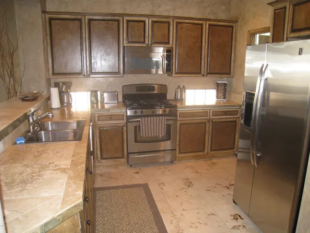 a kitchen with stainless steel appliances granite countertop a refrigerator a stove and a sink
