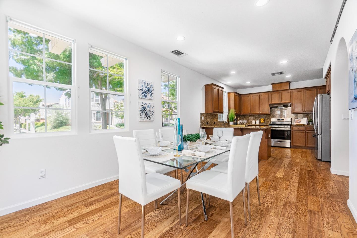 4232 Astor Hollow Street San Ramon, CA 94582 - Photo 9 of 37 a kitchen with stainless steel appliances kitchen island granite countertop a refrigerator a stove top oven a dining table and chairs with wooden floor