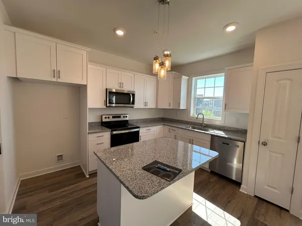 a kitchen with granite countertop a stove sink and microwave