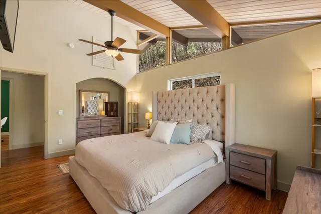 a bedroom with a large bed and wooden floor