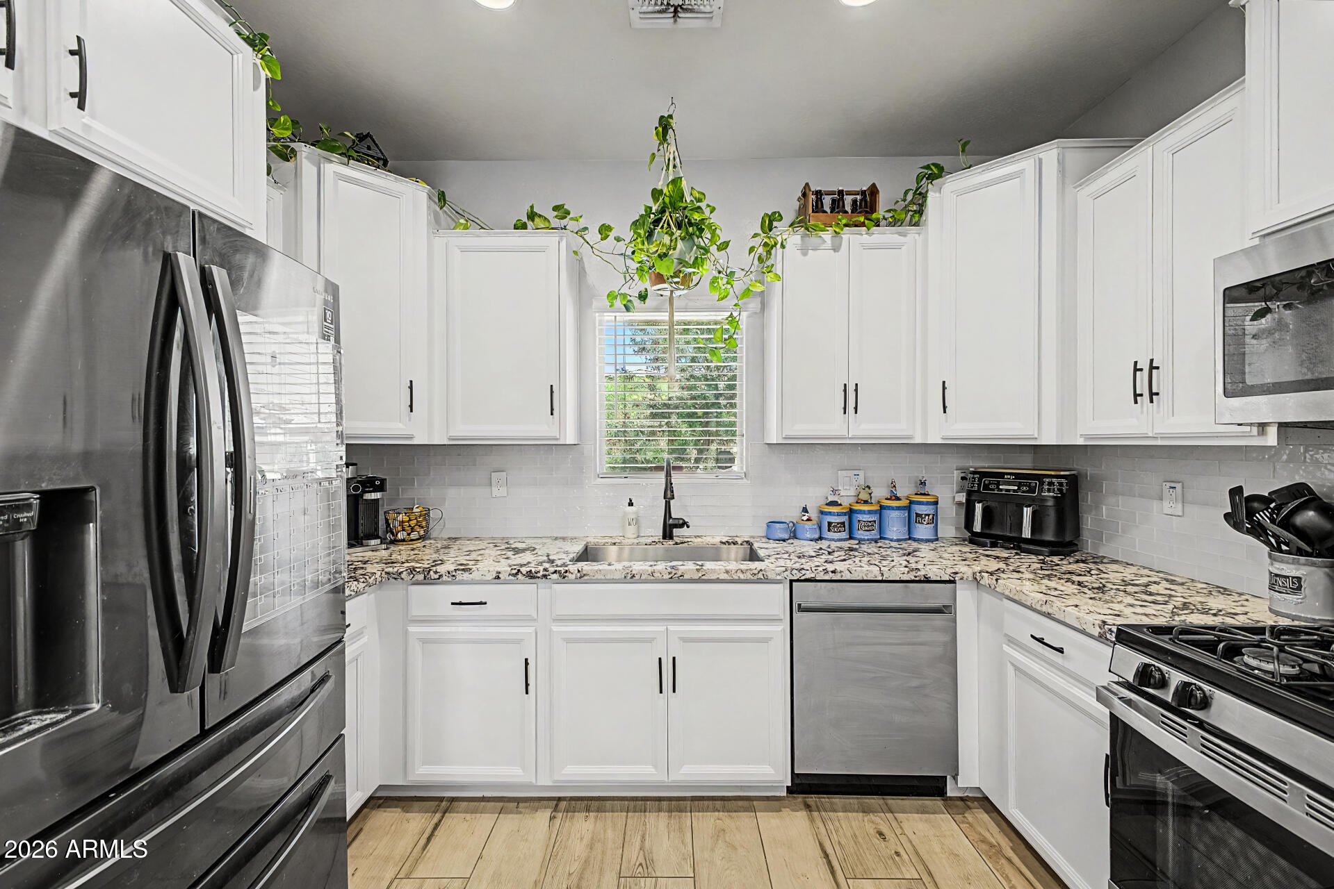 16719 West Rowel Road Surprise, AZ 85387 - Photo 7 of 28 a kitchen with white cabinets sink and stainless steel appliances