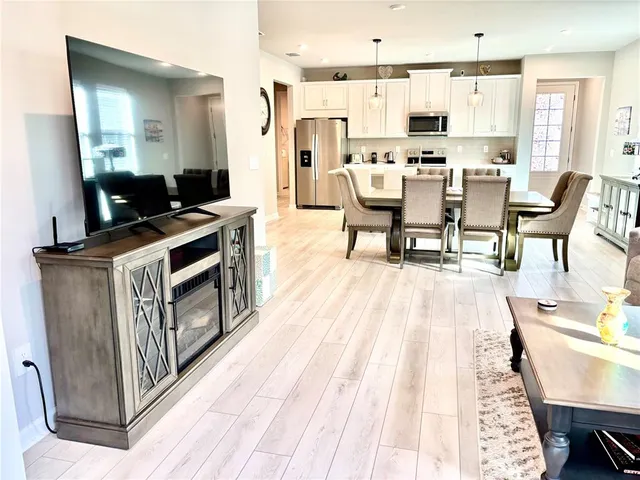 a living room with stainless steel appliances kitchen island granite countertop furniture a rug and a chandelier