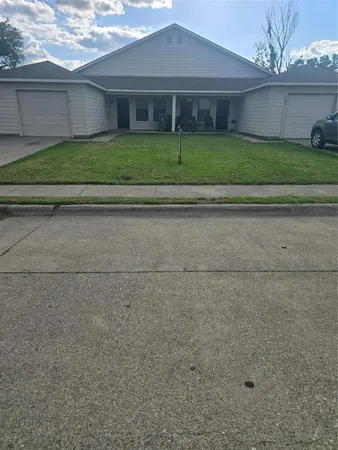 a view of a brick house next to a yard and large trees