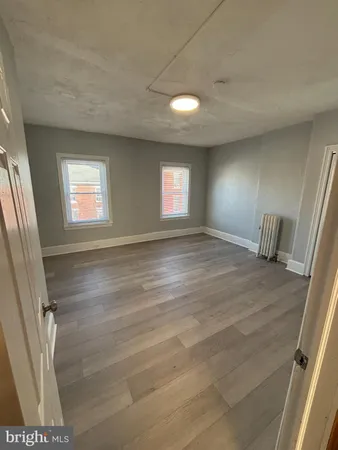 a view of an empty room with wooden floor and windows