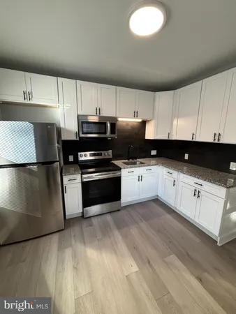 a kitchen with granite countertop a refrigerator sink and cabinets