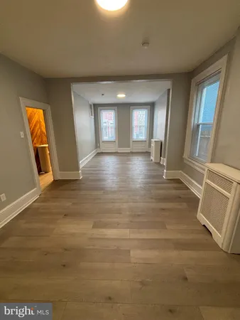 a view of an empty room with window and wooden floor