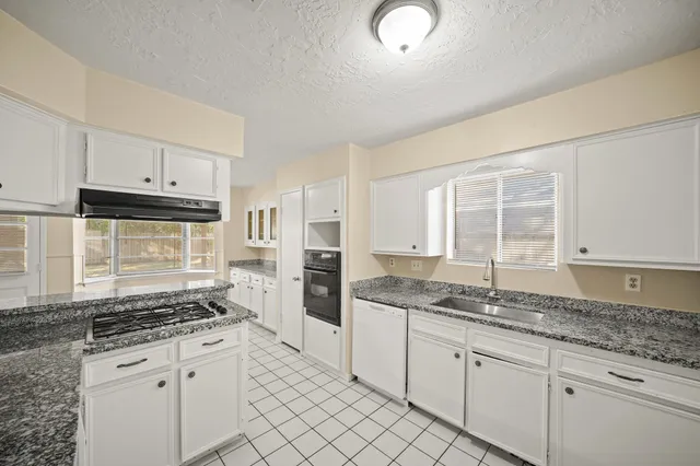 a kitchen with granite countertop a stove sink and cabinets