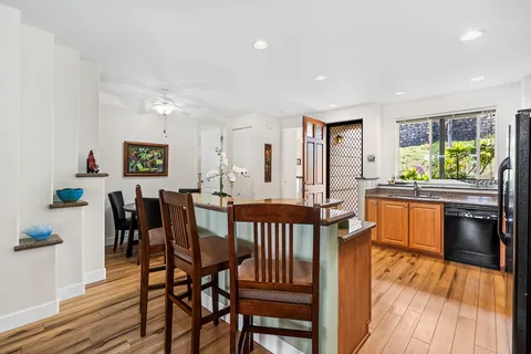a kitchen with stainless steel appliances granite countertop wooden floor dining table and chairs