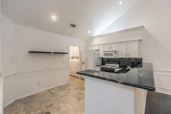 a kitchen with kitchen island granite countertop a sink a stove and a refrigerator