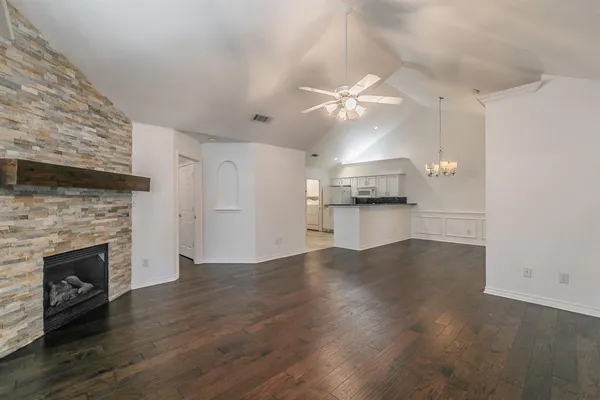 an empty room with wooden floor a fireplace and windows