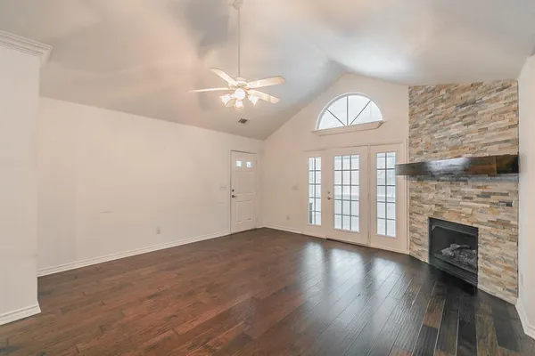 an empty room with wooden floor fireplace and windows