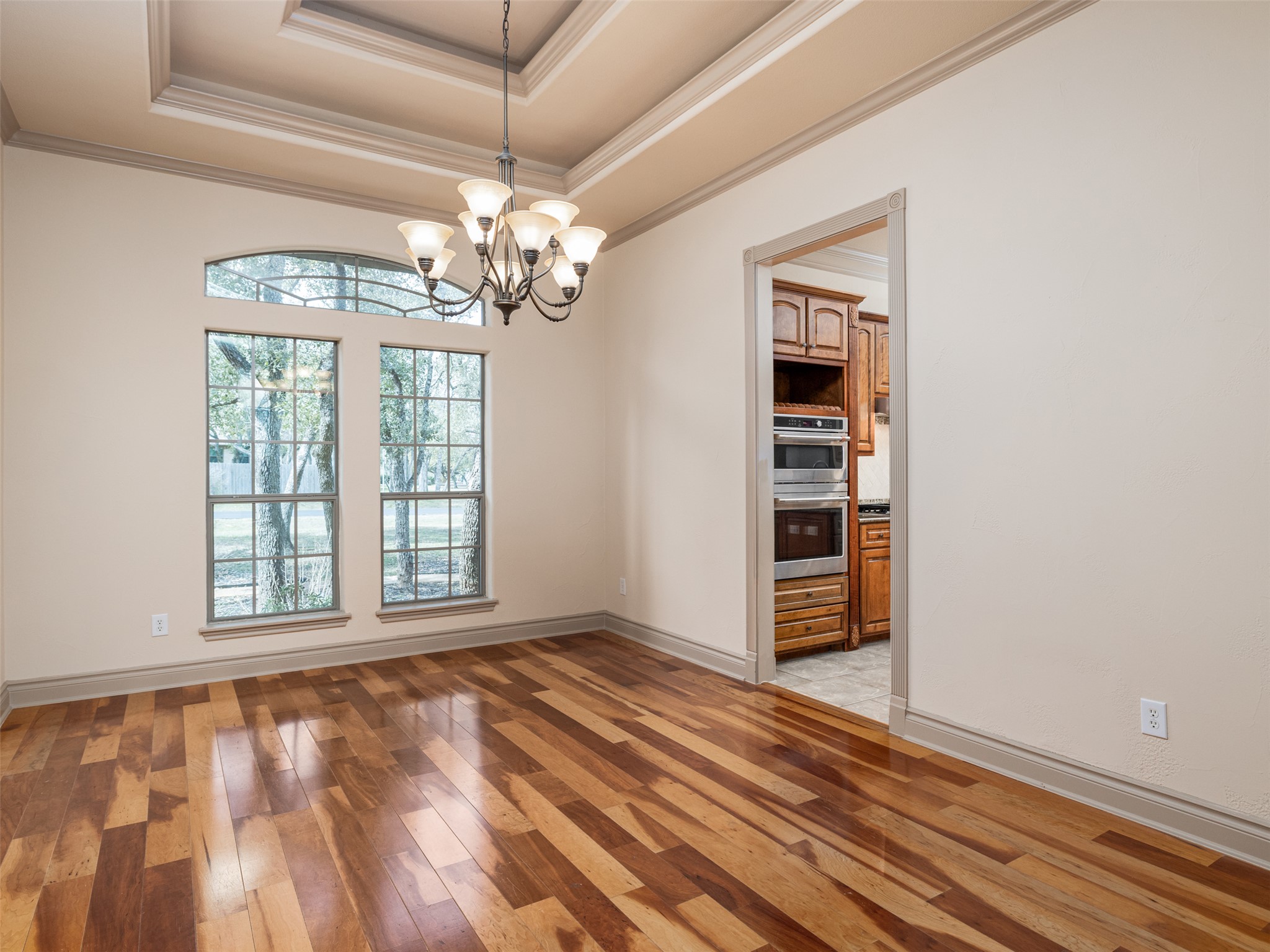 139 Ware Drive Buda, TX 78610 - Photo 13 of 39 Unfurnished dining area with light wood-type flooring, hanging lights, a tray ceiling, and ornamental molding