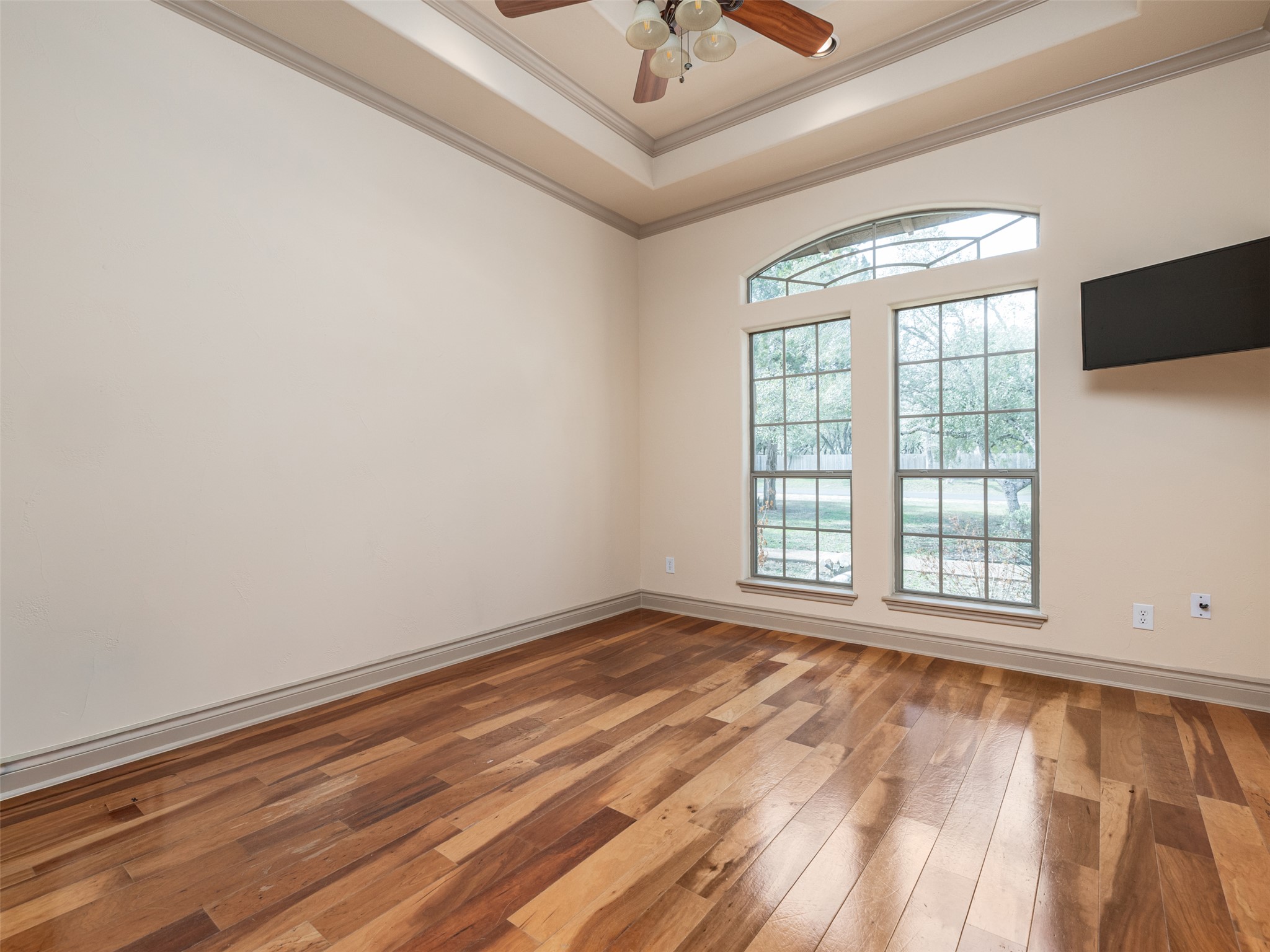 139 Ware Drive Buda, TX 78610 - Photo 14 of 39 Unfurnished room featuring ceiling fan, hardwood / wood-style floors, a tray ceiling, and ornamental molding