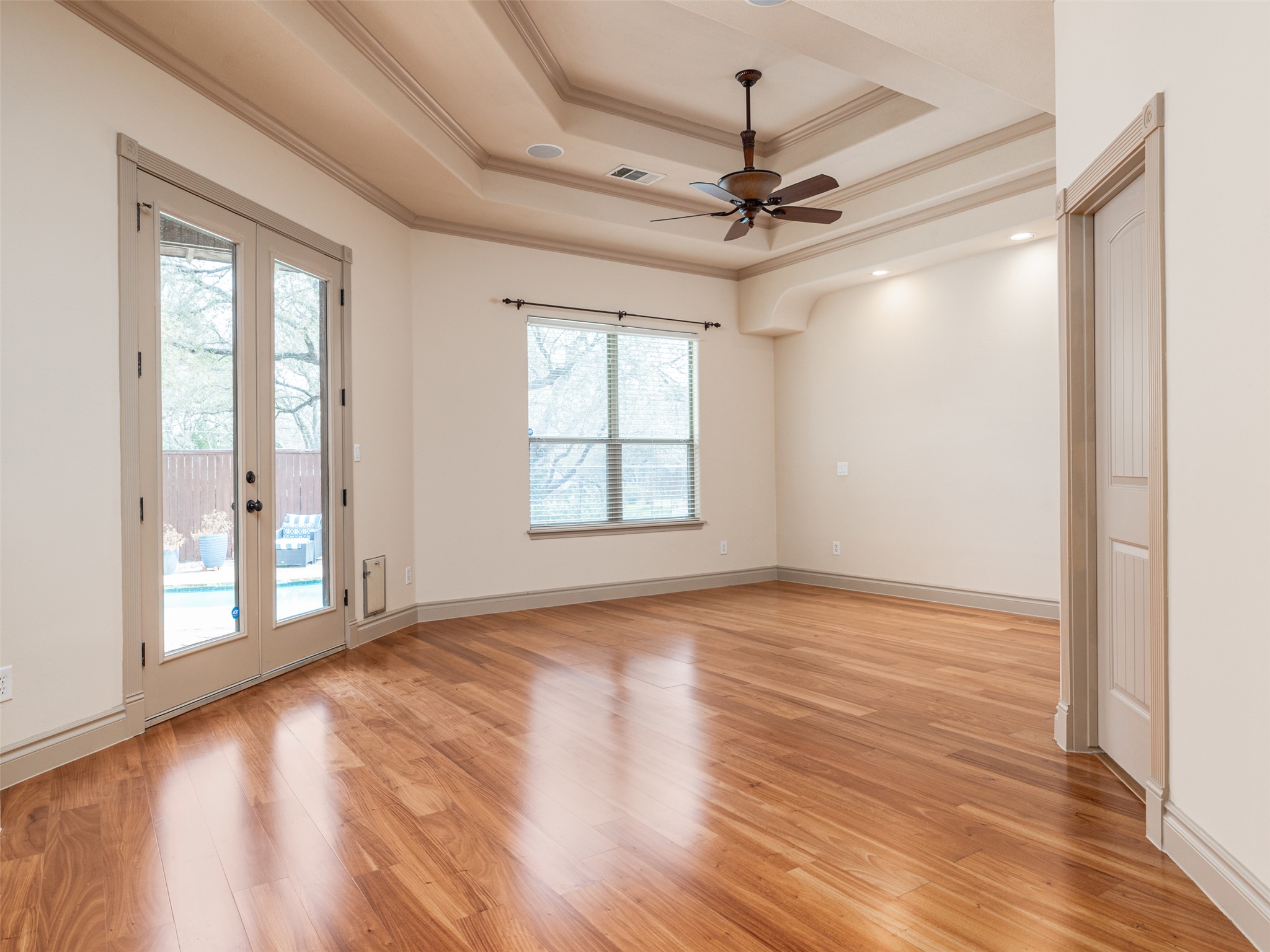 139 Ware Drive Buda, TX 78610 - Photo 15 of 39 Empty room featuring a ceiling fan, light wood finished floors, french doors, crown molding, and a raised ceiling