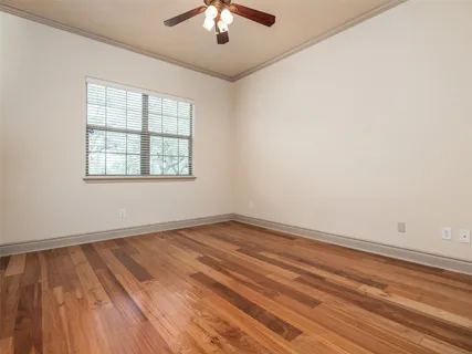 an empty room with wooden floor chandelier fan and windows