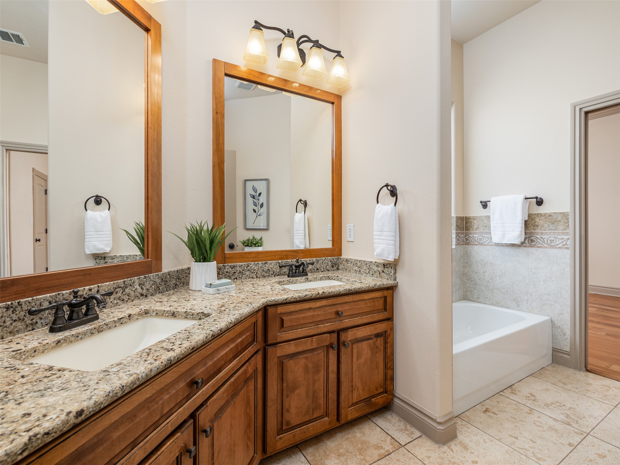 139 Ware Drive Buda, TX 78610 - Photo 23 of 39 Bathroom with double vanity, a garden tub, and light tile patterned floors