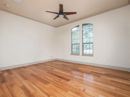 an empty room with wooden floor fan and windows