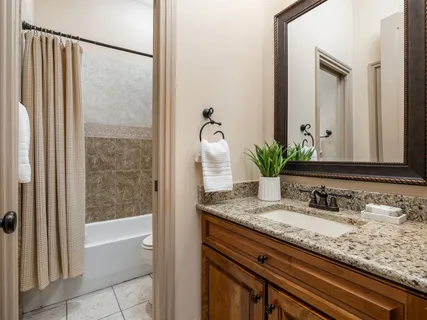a bathroom with a granite countertop sink a mirror and a bathtub