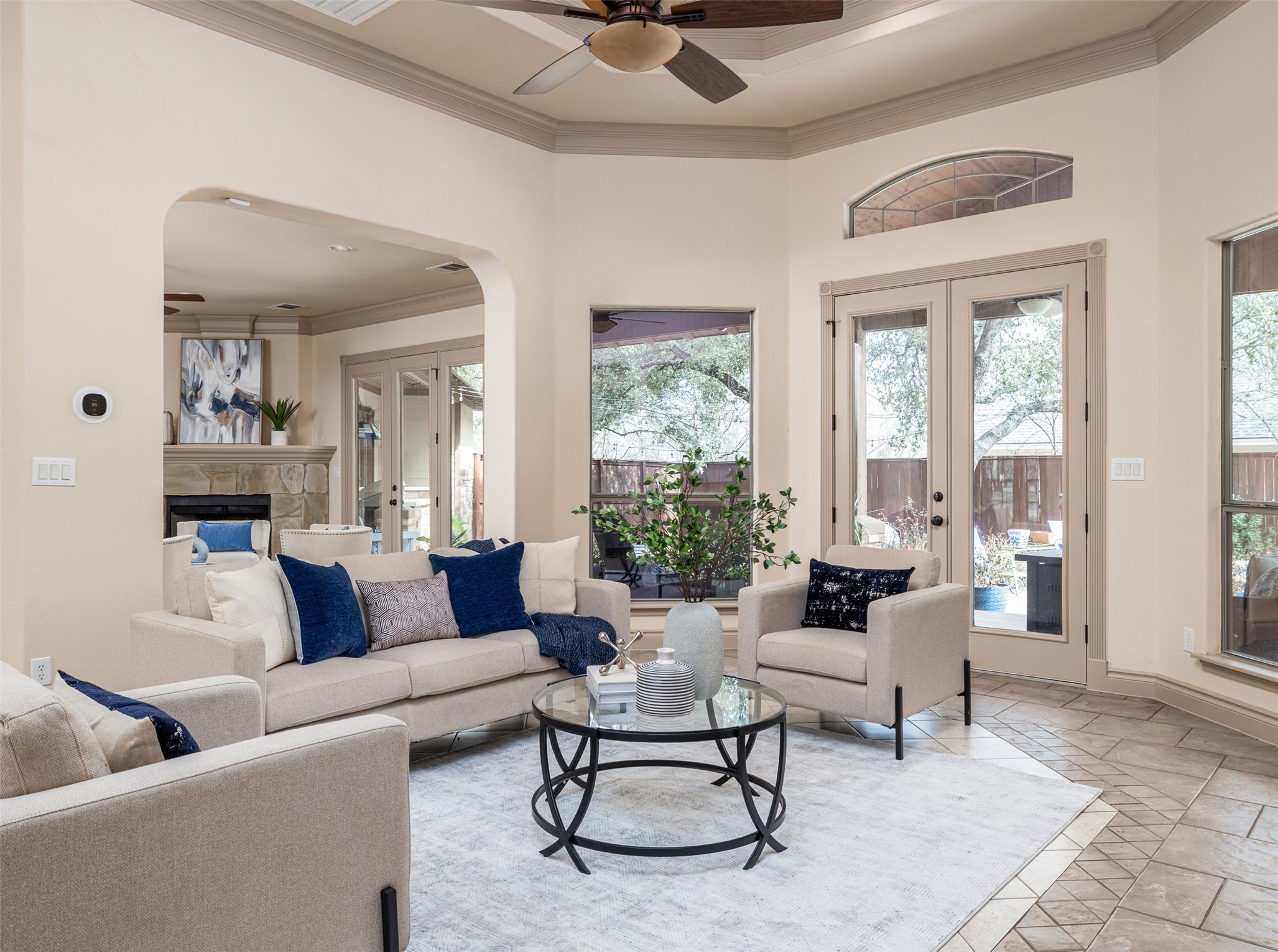 139 Ware Drive Buda, TX 78610 - Photo 3 of 39 Living area featuring french doors, a ceiling fan, crown molding, a high ceiling, and a stone fireplace