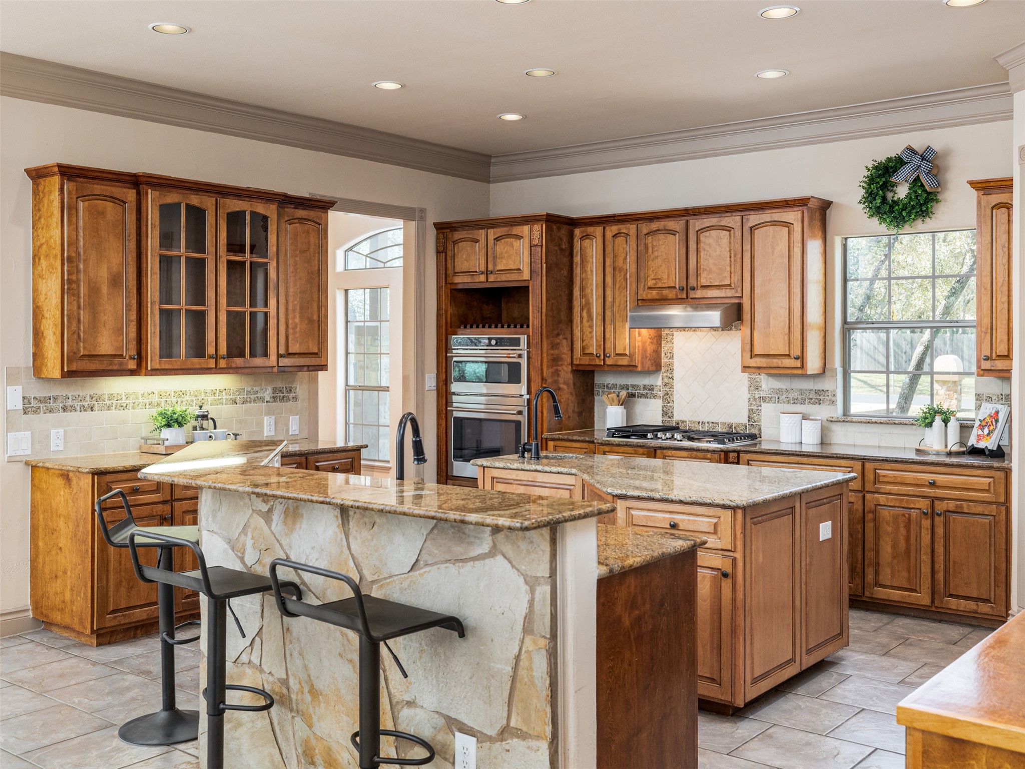 139 Ware Drive Buda, TX 78610 - Photo 7 of 39 Kitchen with wood finish cabinets, tasteful backsplash, light stone counters, stainless steel appliances, and crown molding