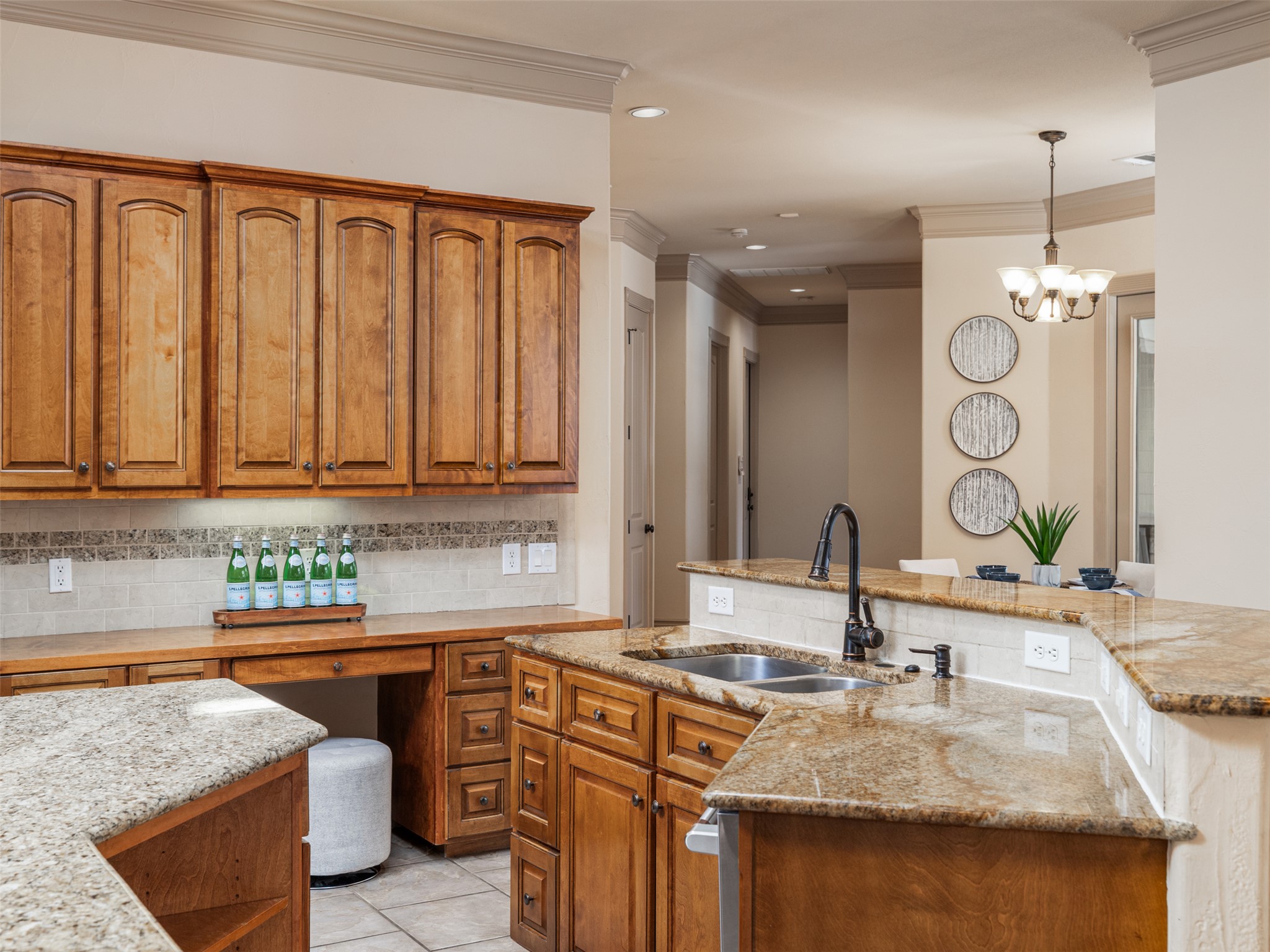 139 Ware Drive Buda, TX 78610 - Photo 10 of 39 Kitchen with wood finish cabinetry, light stone counters, backsplash, a chandelier, and ornamental molding