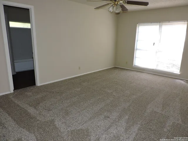 an empty room with a window and a fan
