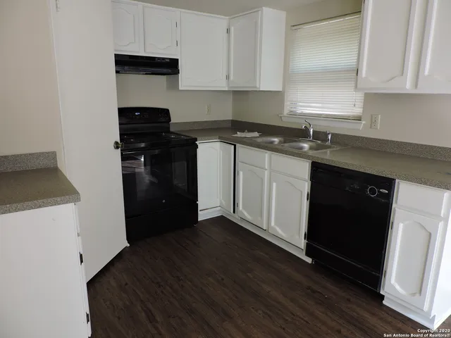 a kitchen with granite countertop white cabinets and black appliances