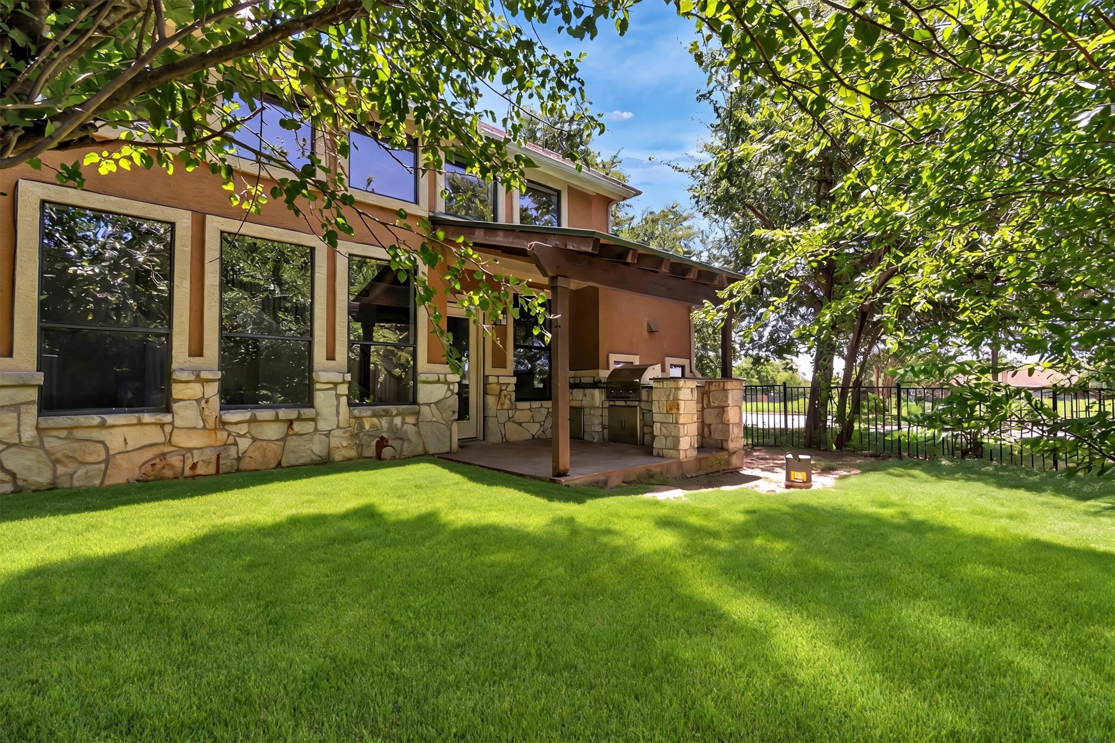 1010 Immanuel Road, Unit 103 Pflugerville, TX 78660 - Photo 29 of 30 A spacious backyard with an outdoor kitchen, lush green lawn, and mature shade trees.
