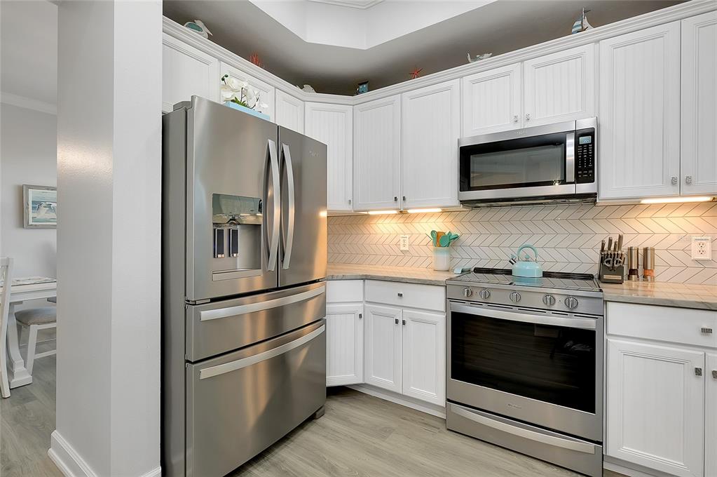 10501 Amberjack Way, Unit 301 Englewood, FL 34224 - Photo 5 of 76 a kitchen with stainless steel appliances white cabinets white stove and a refrigerator