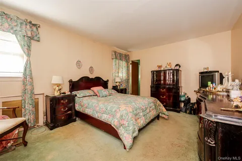 a bedroom with a bed and a flat tv screen on dresser