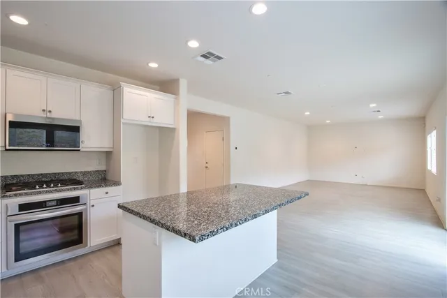 a large kitchen with granite countertop a large counter top stainless steel appliances and windows