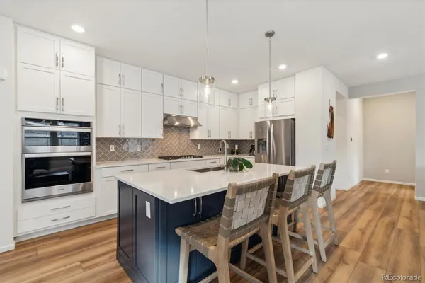 a kitchen with stainless steel appliances kitchen island granite countertop a table chairs stove and refrigerator