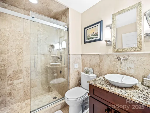 a bathroom with a granite countertop sink toilet a mirror and shower