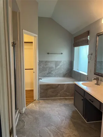 a bathroom with a tub sink and mirror