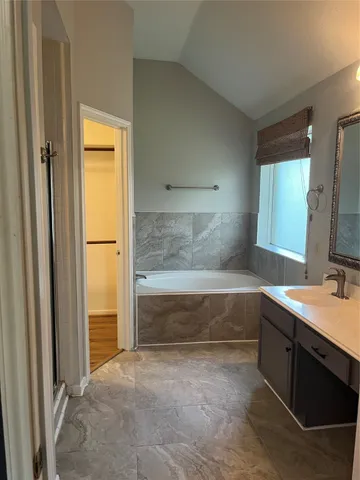 a bathroom with a tub sink and mirror
