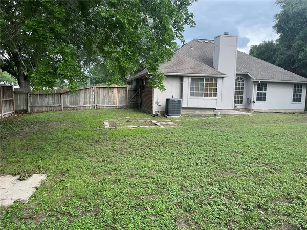 a view of a yard with a large tree and wooden fence
