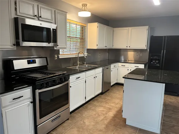 a kitchen with stainless steel appliances a stove microwave and sink