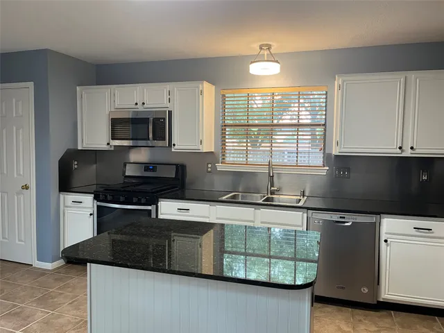 a kitchen with stainless steel appliances granite countertop a stove a sink and a microwave