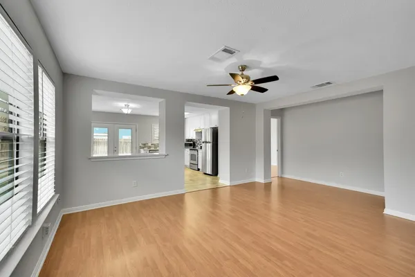 a view of an empty room with a window and wooden floor