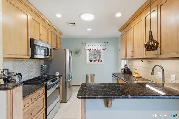 a kitchen with stainless steel appliances granite countertop a sink stove and refrigerator