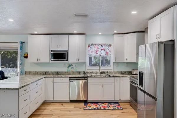 a kitchen with granite countertop a sink stainless steel appliances and white cabinets