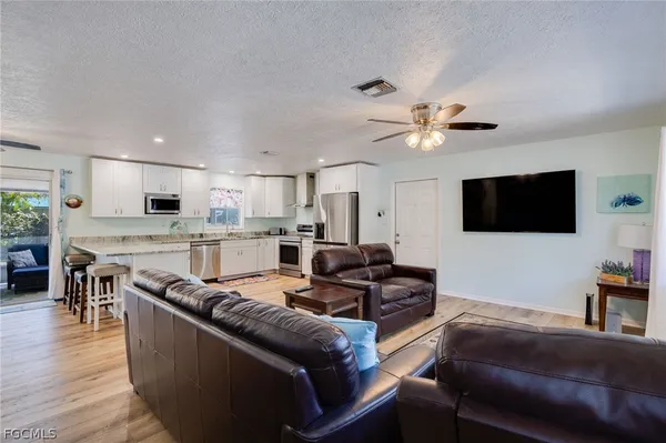 a living room with furniture kitchen view and a flat screen tv