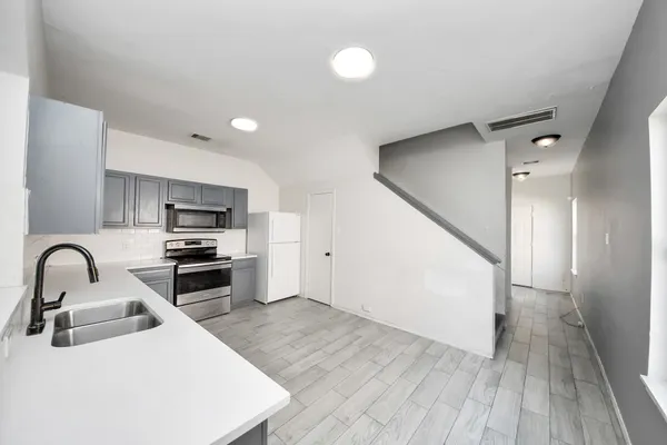 a kitchen with stainless steel appliances a sink a stove top oven and wooden floor