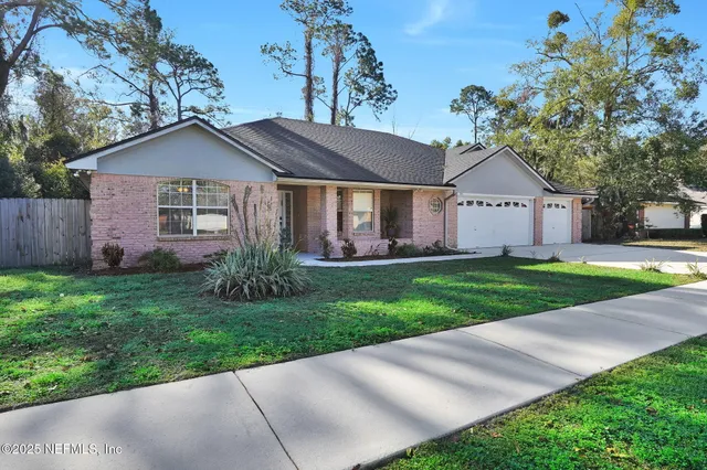 a view of a house with a big yard plants and large trees